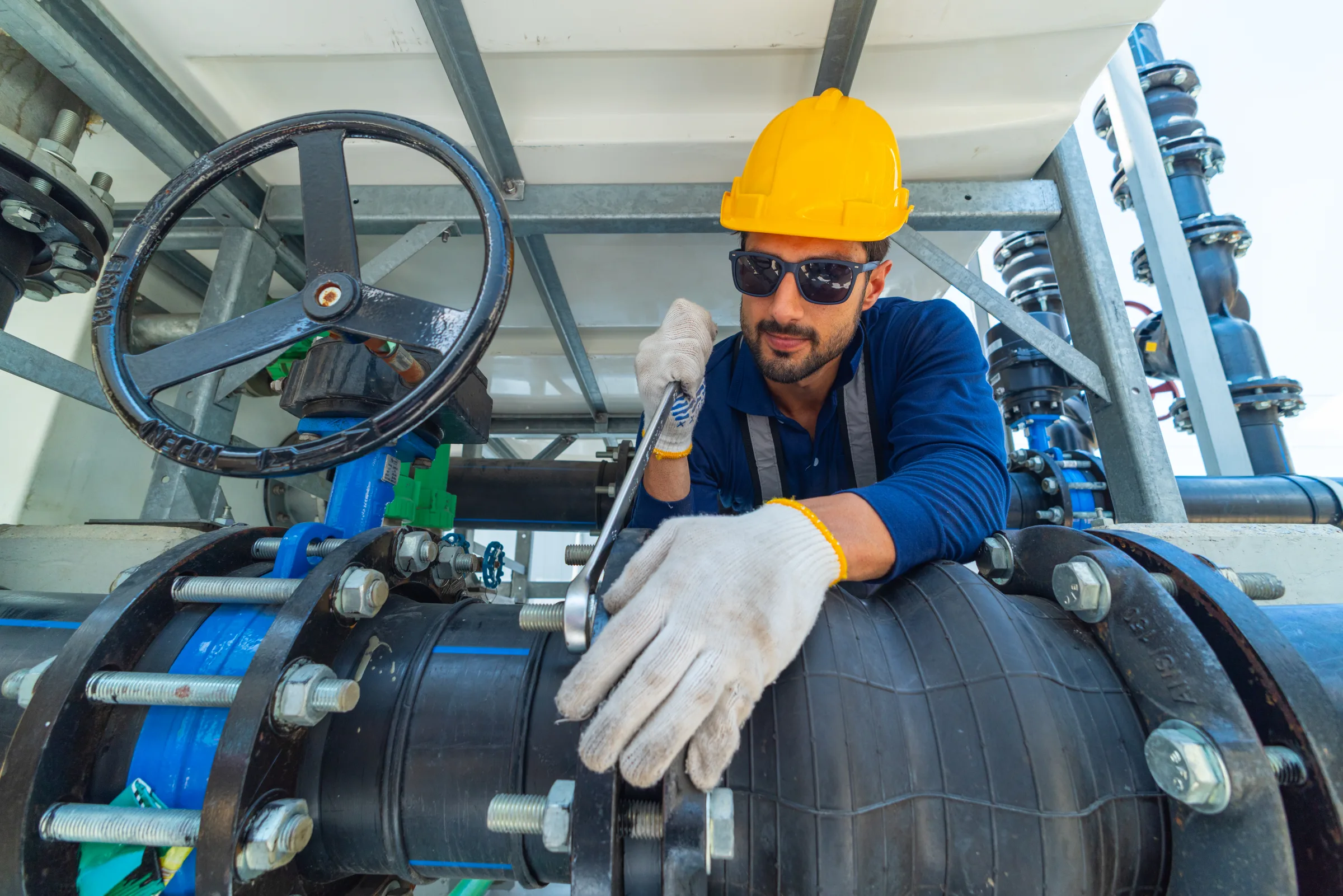 Technician working on a large valve in an industrial piping system
