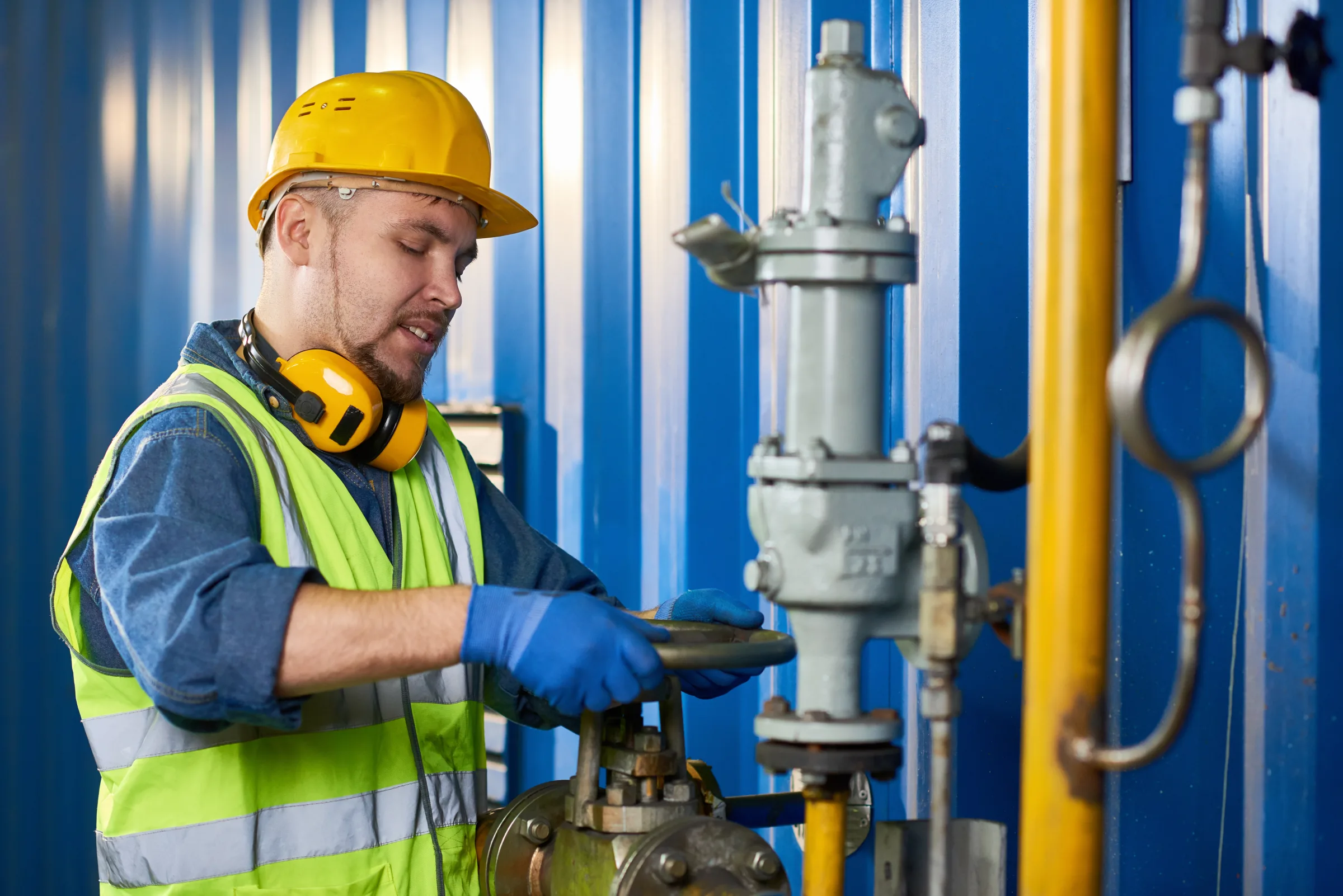 Technician inspecting a valve at an industrial piping system