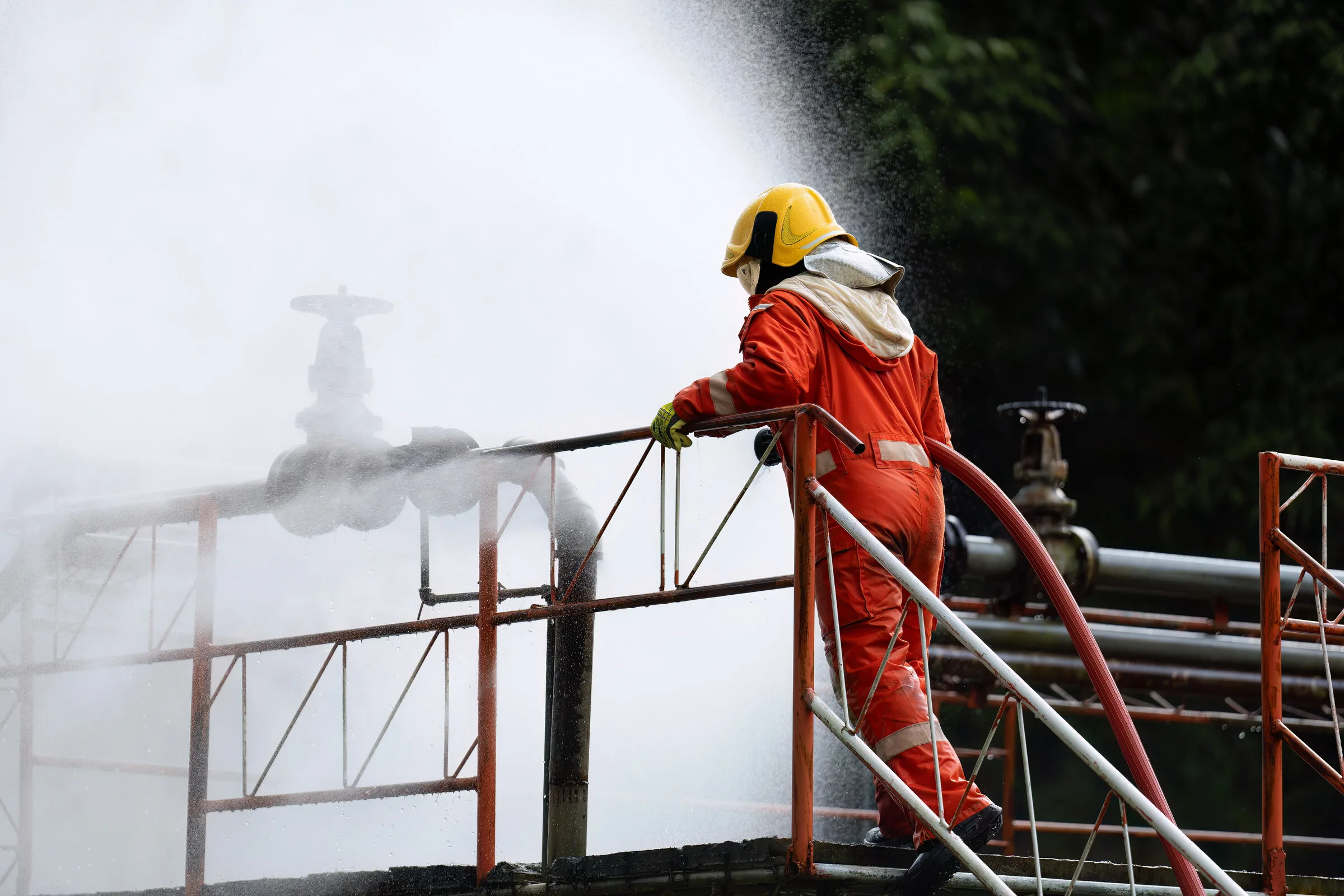 Worker in safety suit working near a high-pressure water spray